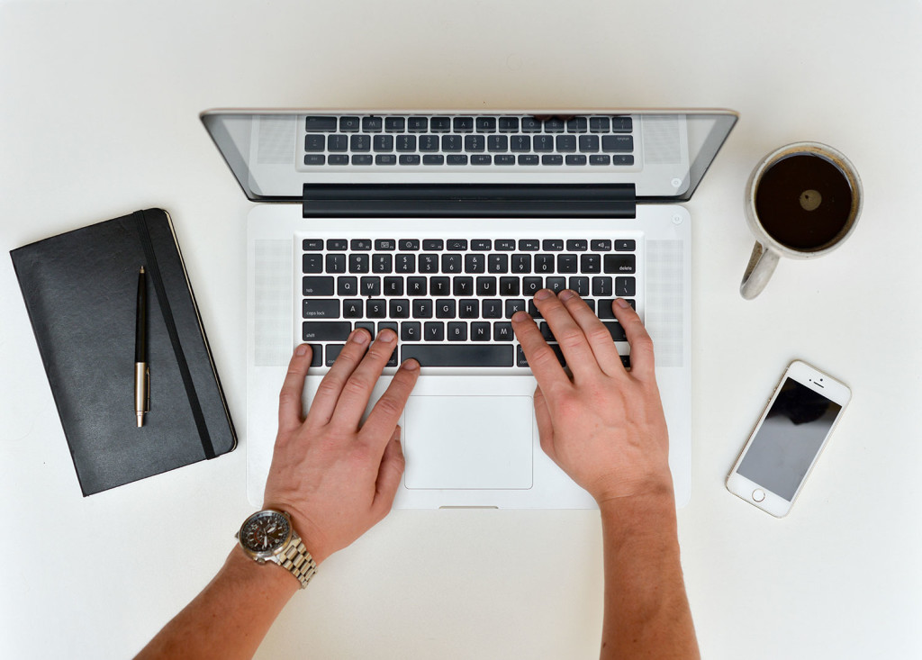 Mans Hands Typing On Laptop With Smartphone Book And Coffee 1024x733